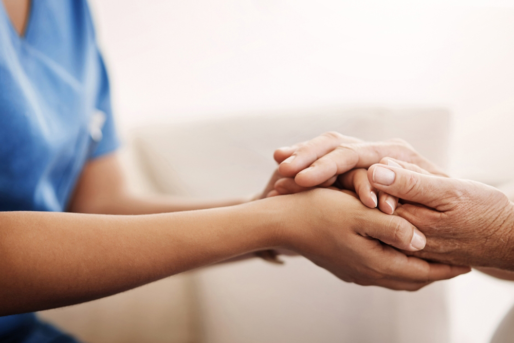 Support, nurse and senior woman holding hands on sofa for health, consulting or compassion. Help, caregiver and elderly patient with care for hope, trust or medical conversation at retirement home