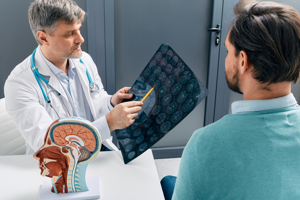 Doctor explaining to male patient results of MRI scan of his brain. Diagnosis of diseases and head injuries